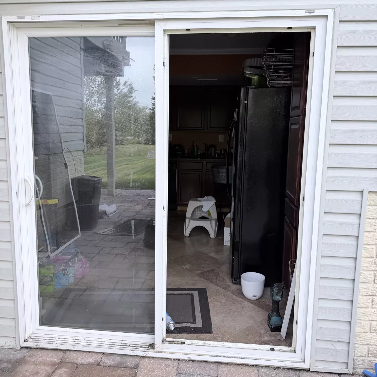 Sliding patio door partially removed with tools visible during installation