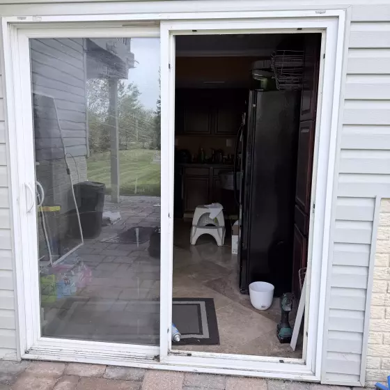 Sliding patio door partially removed with tools visible during installation