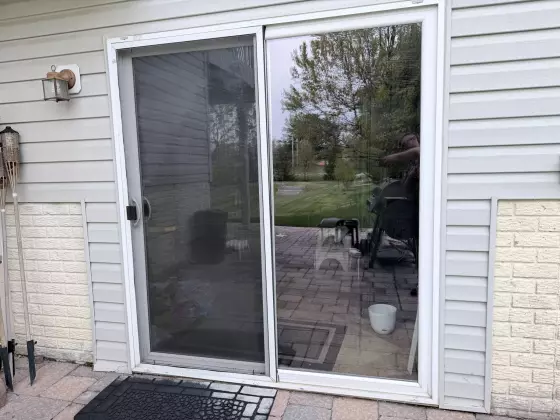Exterior view of a residential sliding glass door with screen