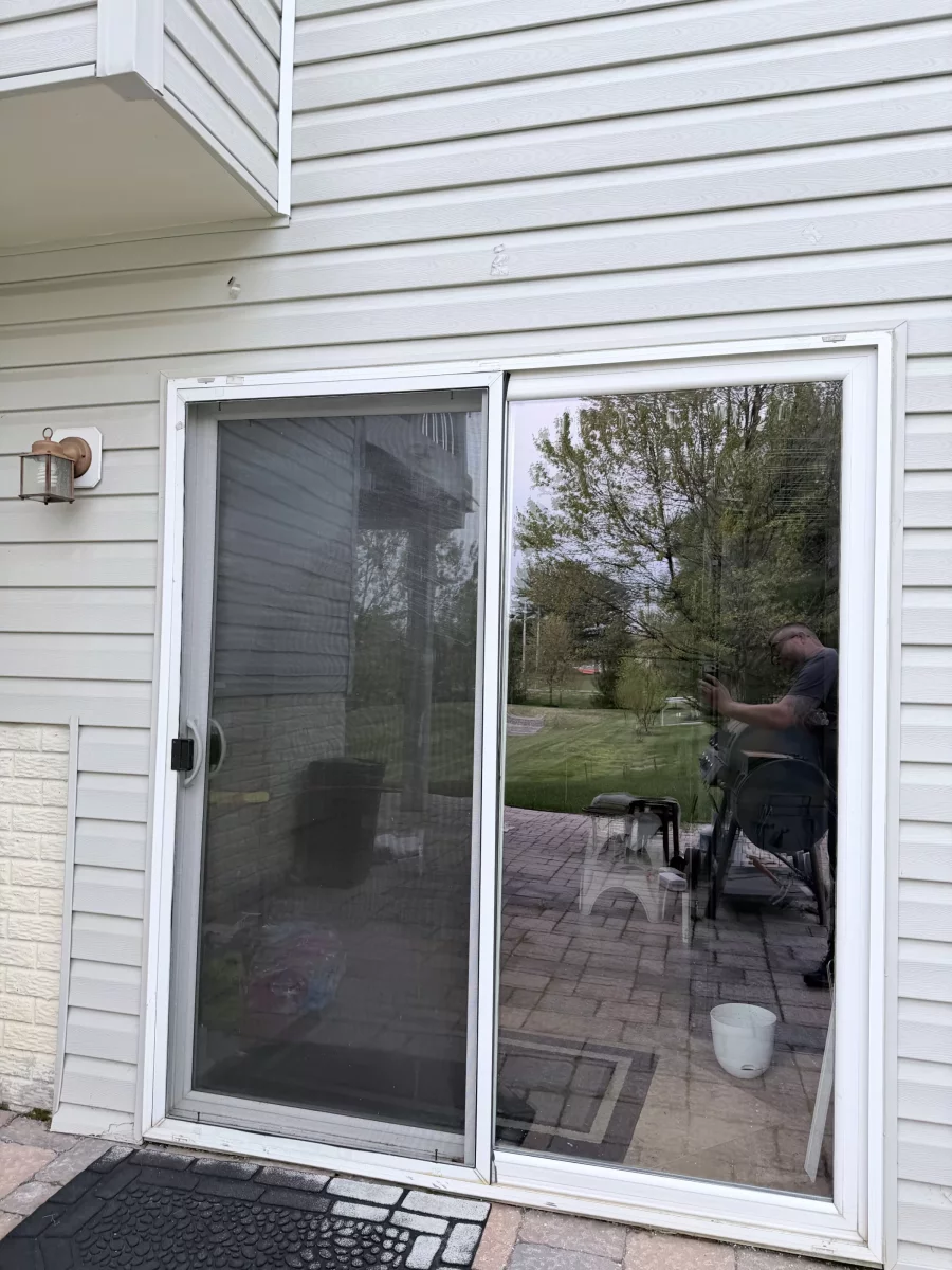 Exterior view of a residential sliding glass patio door with screen