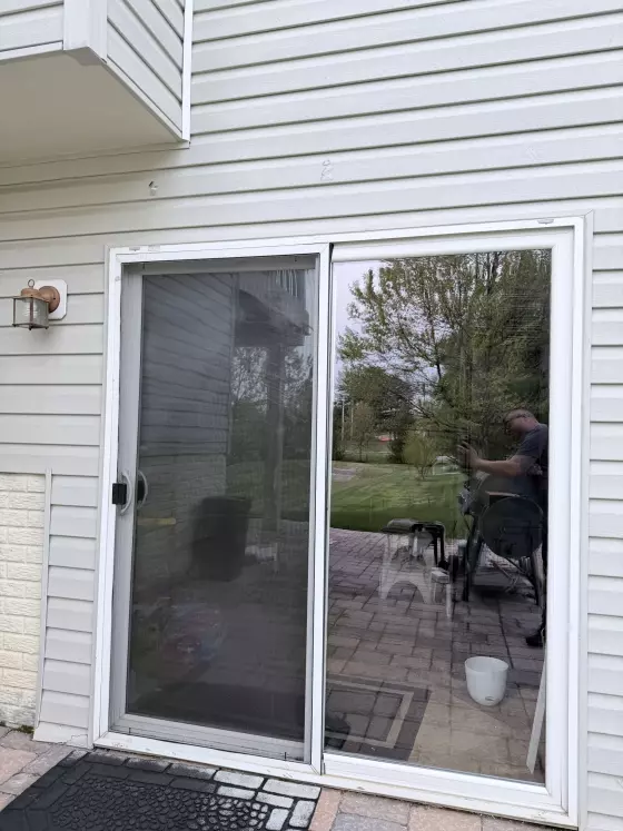 Exterior view of a residential sliding glass patio door with screen