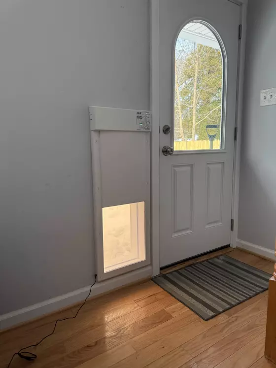 Installed pet door in a white entry door with hardwood floor