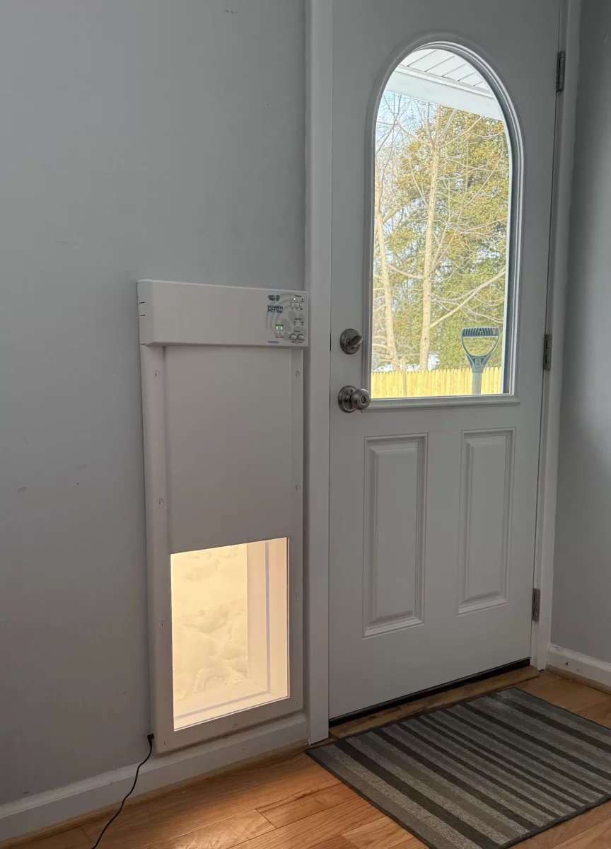 Installed pet door next to an entry door on a hardwood floor