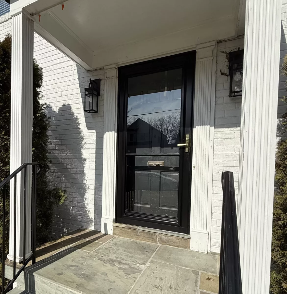Exterior view of a house entry with a glass door and stone steps
