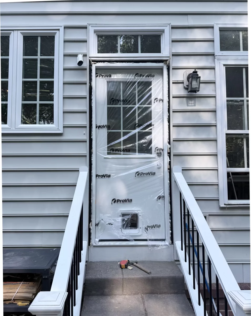 Exterior door with protective film and pet door being installed