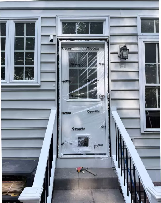 Exterior door with protective film and pet door being installed
