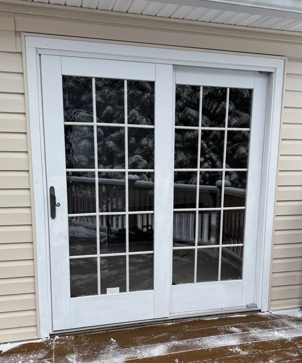 White patio door with glass panels on a snowy deck