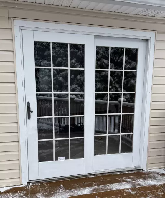 White patio door with glass panels on a snowy deck