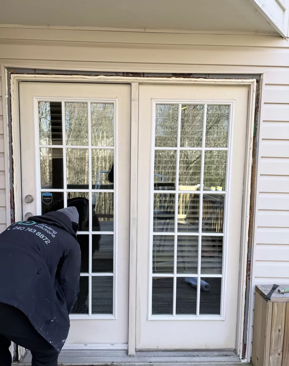 Person working on exterior french door installation with tools visible