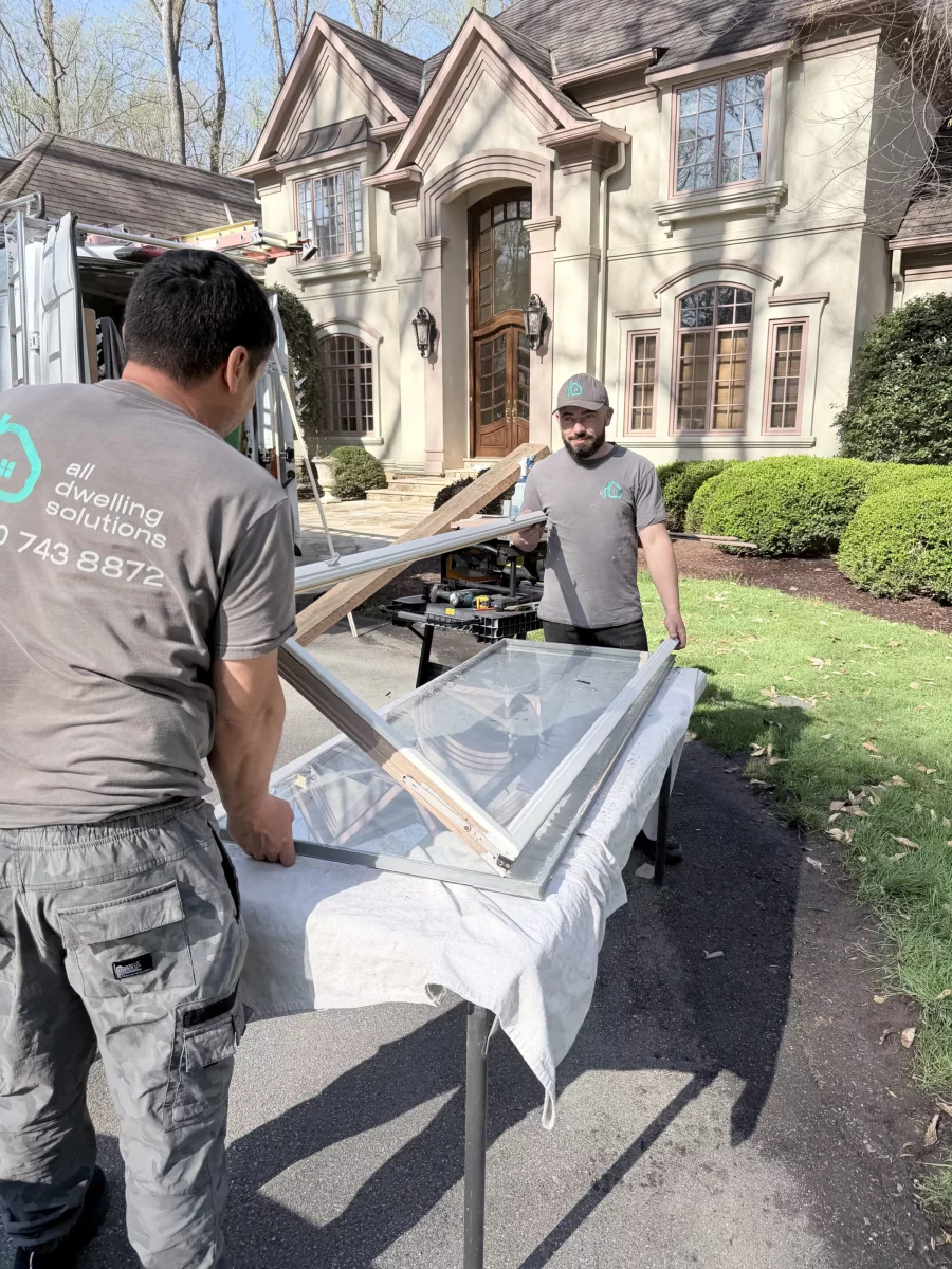 Two workers handling a window sash outside a residential house