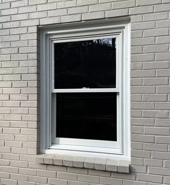 White framed window installed in painted brick exterior wall