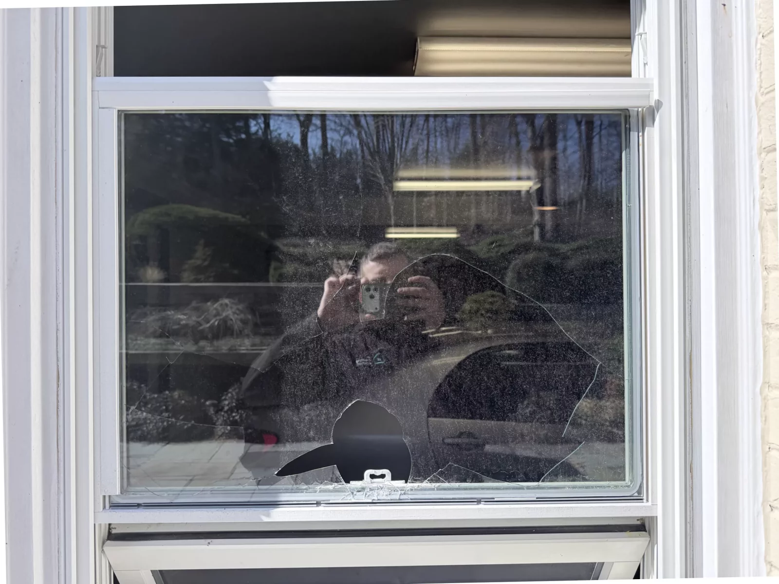 Broken glass in residential window with person reflected