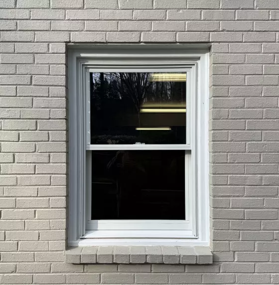 White framed window installed in painted brick exterior wall
