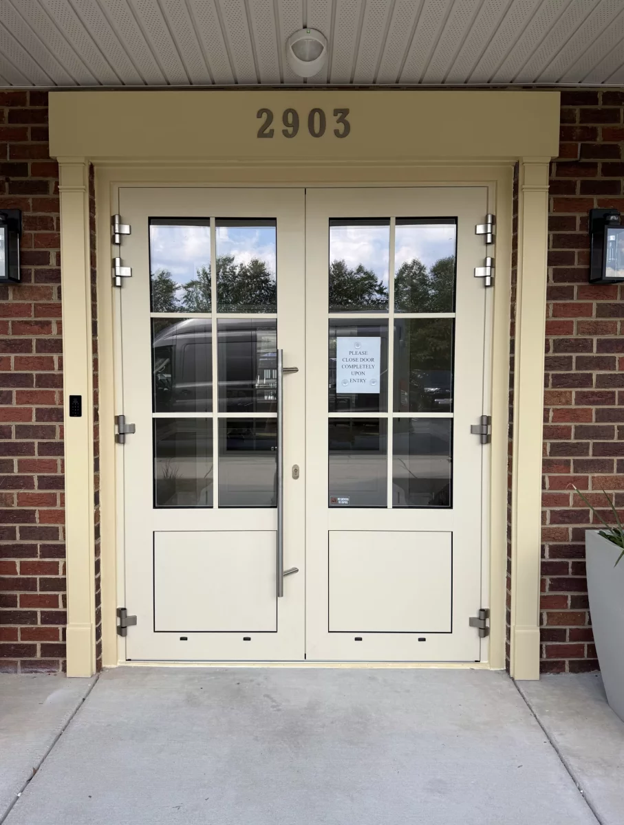 Double glass entry doors with brick exterior and metal handles