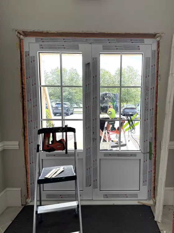 French door installation in progress with ladder and tools visible