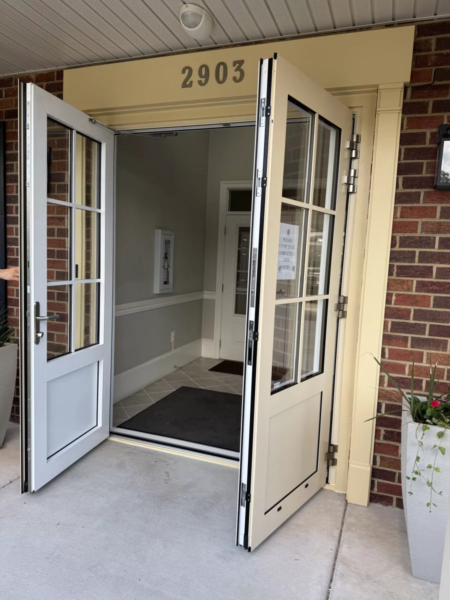 Double entry doors with glass panels open at building entrance