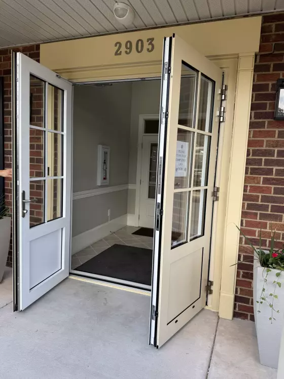 Double entry doors with glass panels open at building entrance