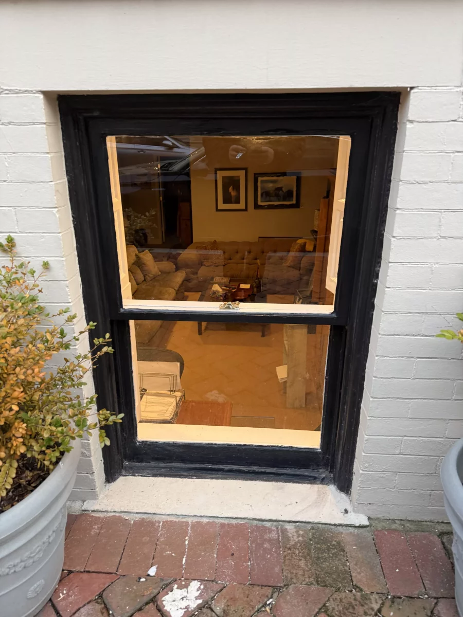 Exterior view of a window with black trim and brick surroundings