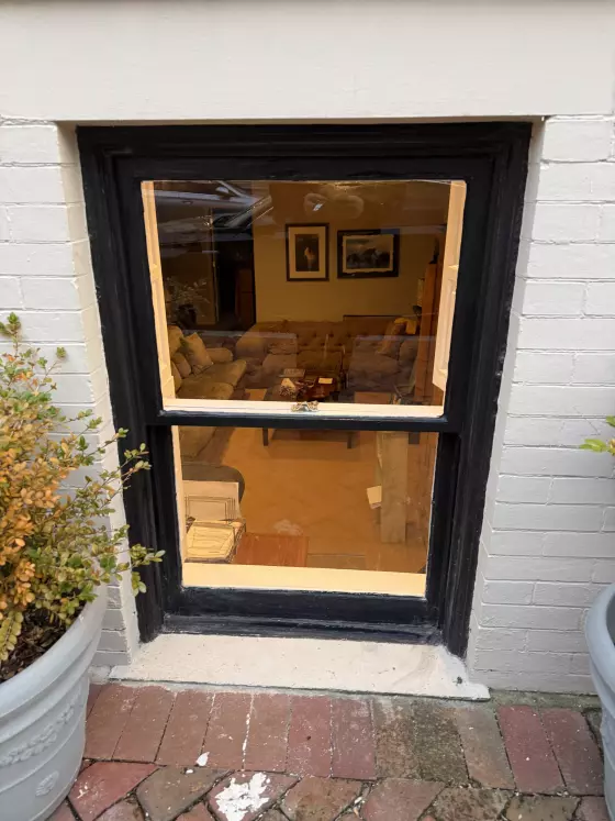 Exterior view of a window with black trim and brick surroundings
