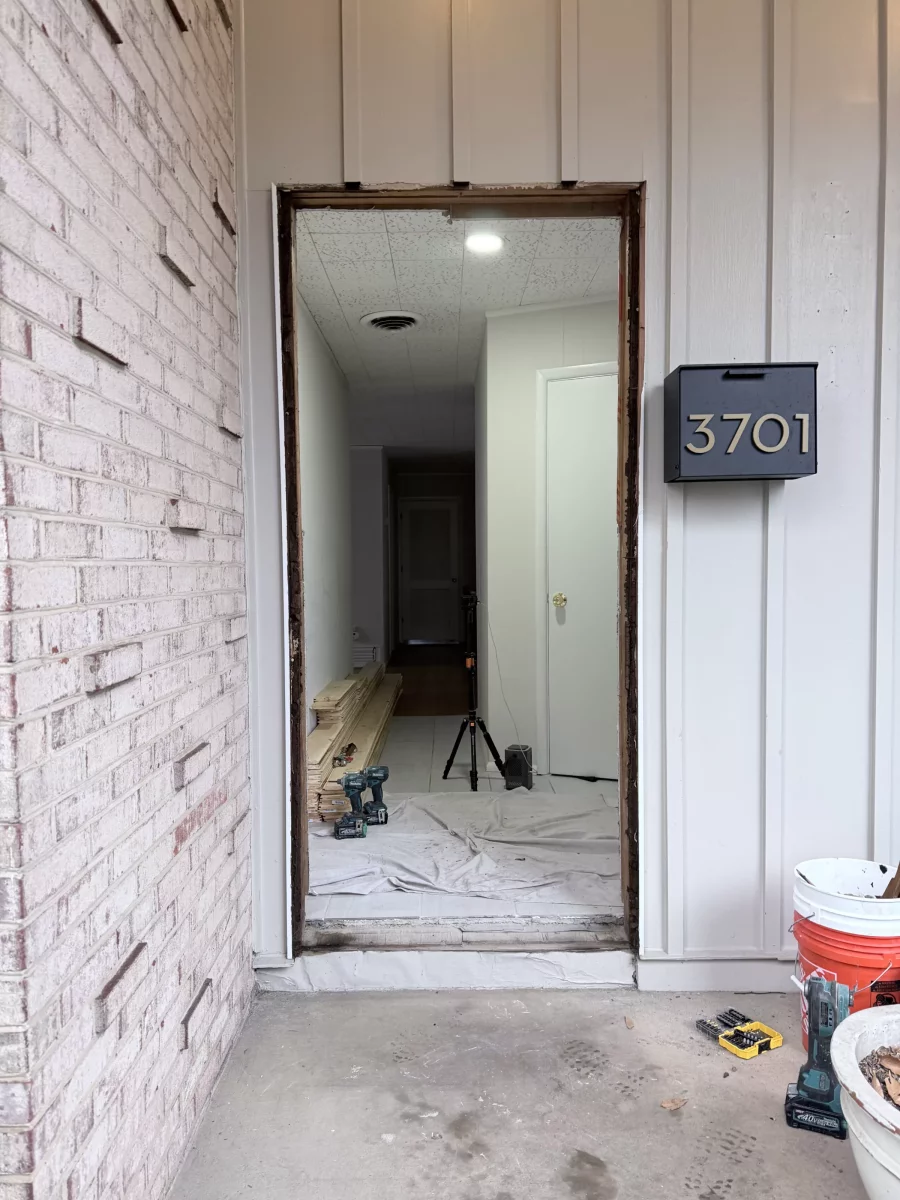 Front door opening under construction with tools and materials visible
