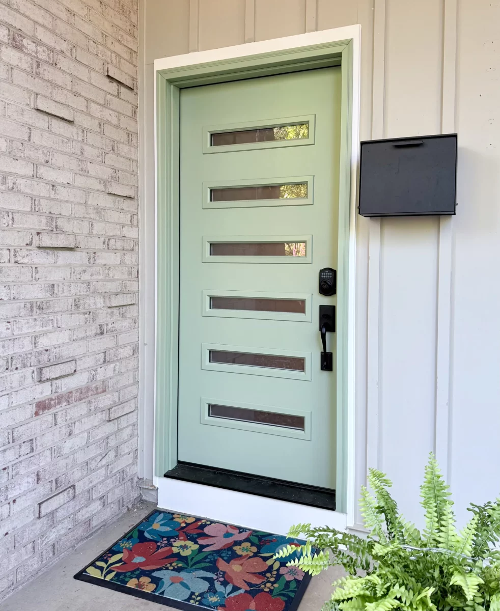 Modern entry door with horizontal glass panels and floral doormat