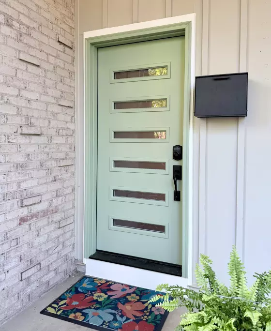 Modern entry door with horizontal glass panels and floral doormat