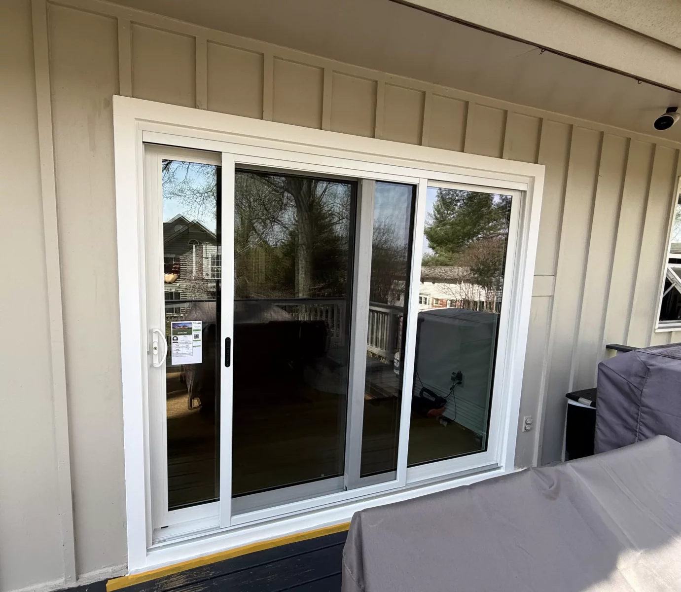 White sliding patio door installed on exterior deck with beige siding