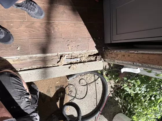 rotted door threshold with debris and damaged wood visible