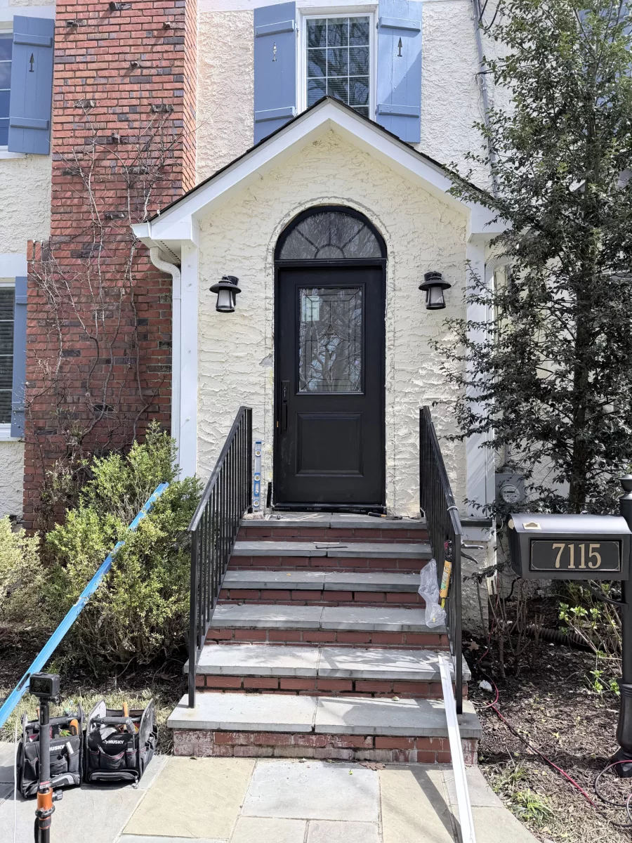 Black entry door installation in progress on residential home exterior