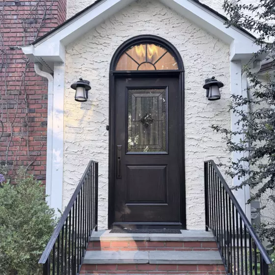 Front entry door with glass panel and brick steps on residential home