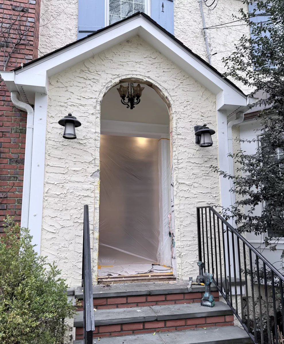 Residential entry door opening prepared for installation with tools and plastic sheeting visible