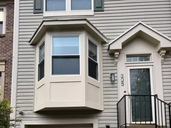 Residential building exterior with bay window, siding, entry door, and garage door