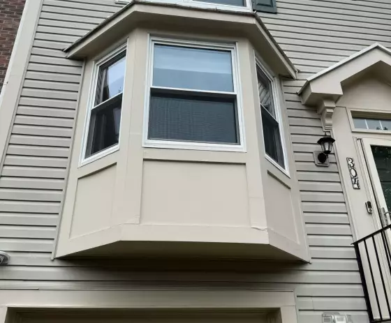 Exterior view of a house with bay window and siding above a garage door