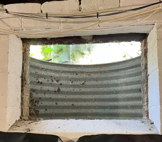 Basement window opening with exposed concrete and metal window well