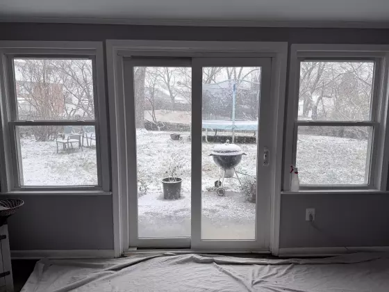 Sliding patio door and windows with drop cloth on floor inside room.