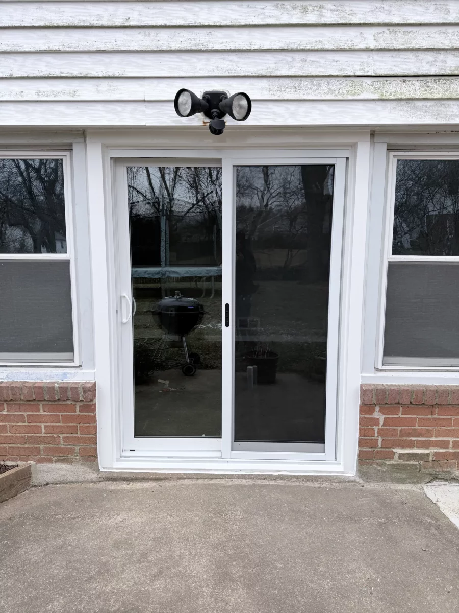White sliding patio door installed on brick exterior wall