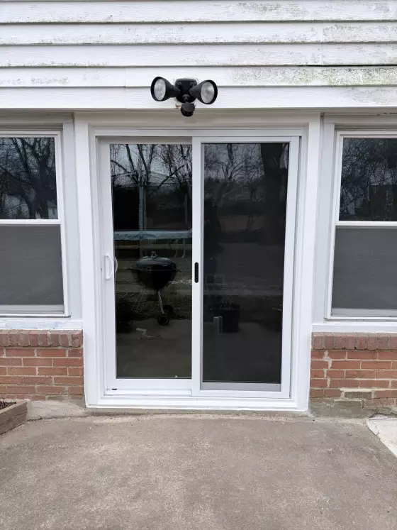 White sliding patio door installed on brick exterior wall