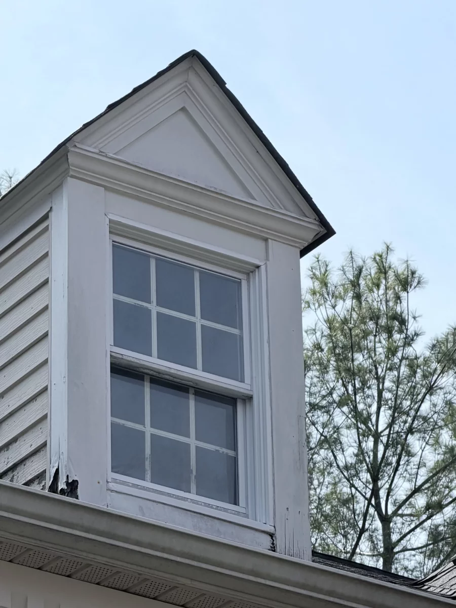 Exterior window with visible rot and damaged trim on residential dormer.