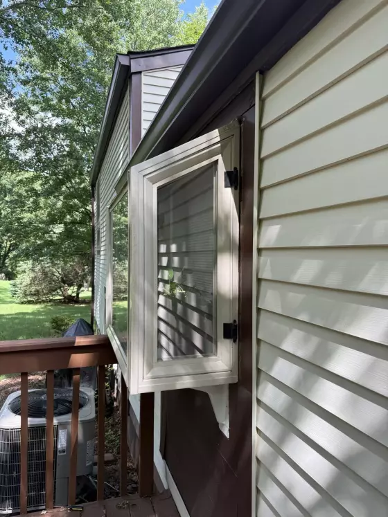 Exterior view of open casement window with siding and deck