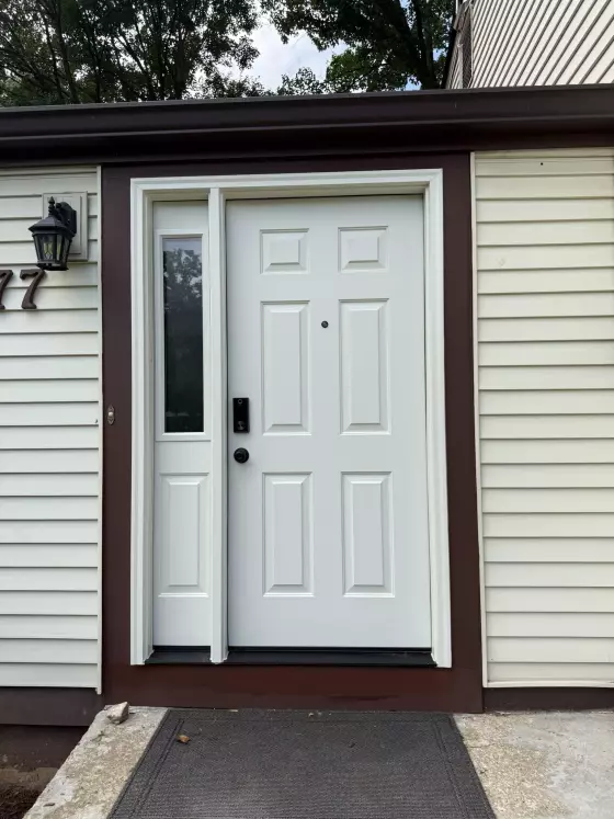 White entry door with side window and brown trim on residential exterior