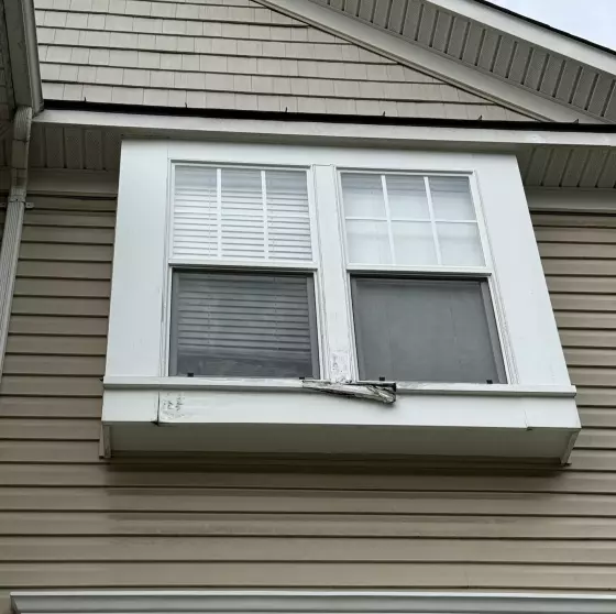 Exterior view of upper story window with visible rot on trim