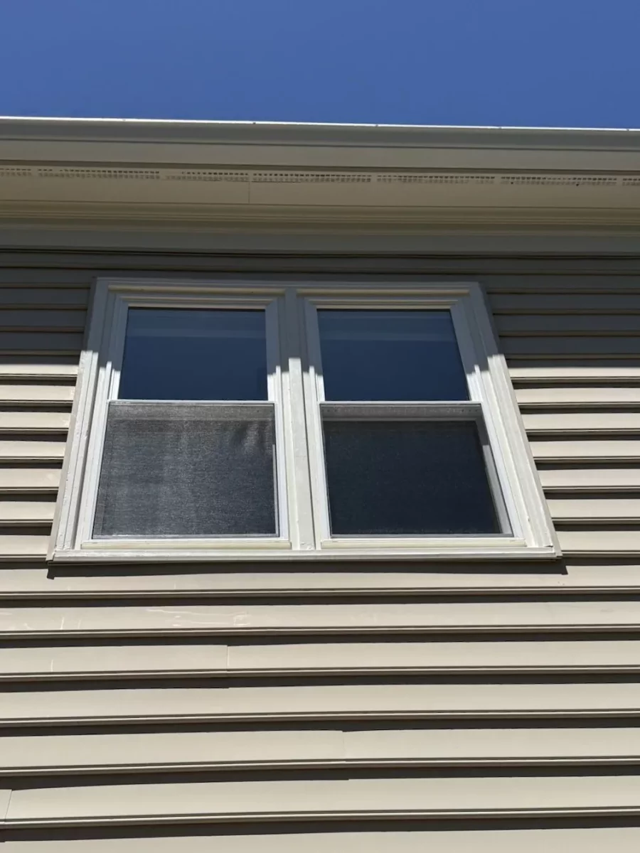 Two white double-hung replacement windows professionally installed with exterior trim in Rockville, MD.