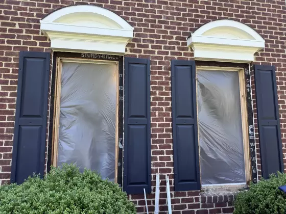 Two window openings with protective film on brick house exterior