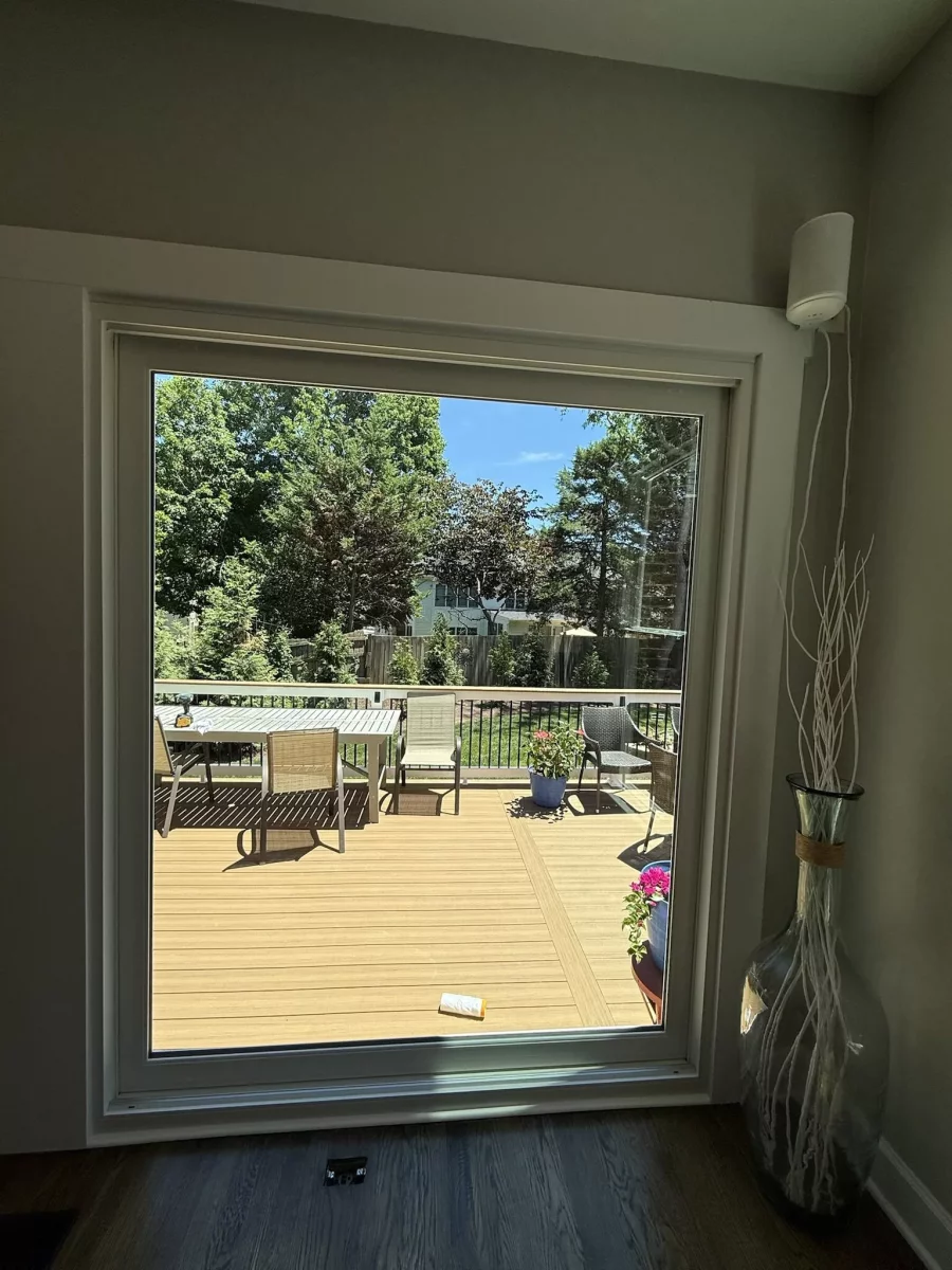 Large window with white frame overlooking deck and outdoor furniture
