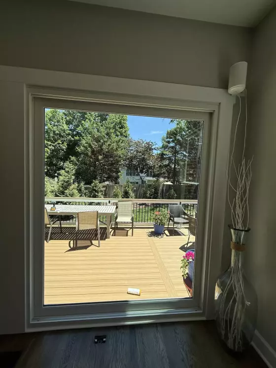 Large window with white frame overlooking deck and outdoor furniture