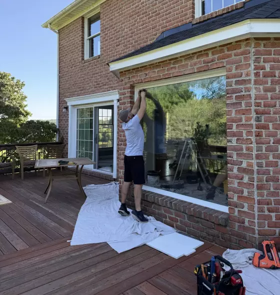 Person installing large window in brick exterior wall