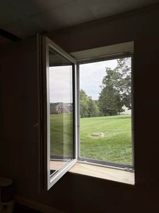 Open tilt and turn window with view of grass and trees