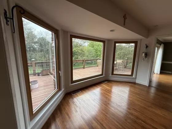 Three large Oknoplast  windows with wood trim overlooking a deck and trees