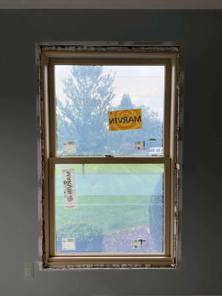New window partially installed in interior wall with exposed frame