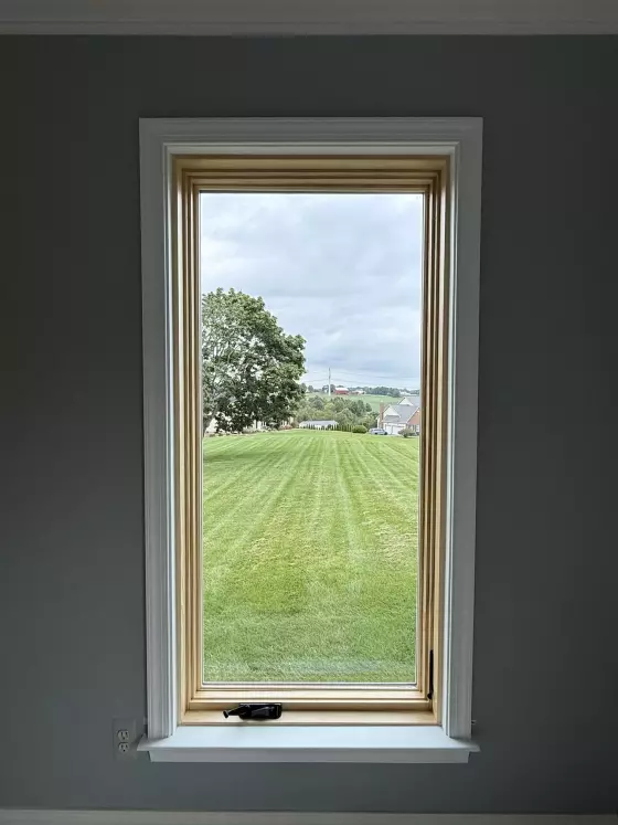 New Marvin Elevate casement window shown after full-frame replacement, with a natural-wood interior and finished white trim.